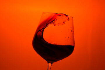 Red wine in a glass on a red background.