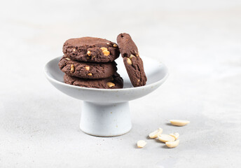Chocolate cookies with whole peanuts in a ceramic vase on a light gray background