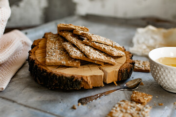 Healthy and nutritious diet bread with sesame and sunflower seeds on a thin crunchy malt base. Near natural bee honey and a wooden stand sawn