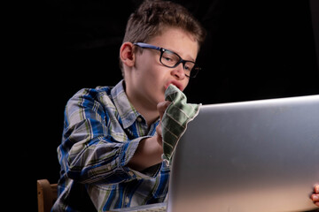 Boy dusts laptop with green cloth