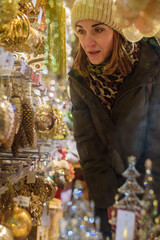 Woman doing Christmas shopping. Looking to decorations through window