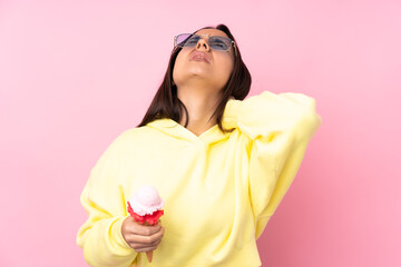 Young brunette girl holding a cornet ice cream over isolated pink background with neckache