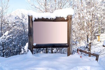 Blank advertising billboard with wood frame  in the snowy  mountains . Empty copy space