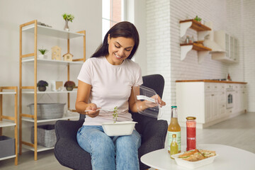 Happy young woman having fresh natural takeaway lunch from plastic food container sitting in an...