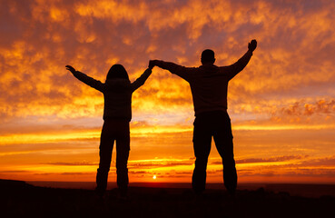 Fototapeta premium A loving couple on the background of a fiery orange sunset.