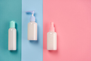 Packagings of cream, lotion, gel, facial foam or skin care on blue and pink background with copy space. Cosmetic beauty product branding mockup