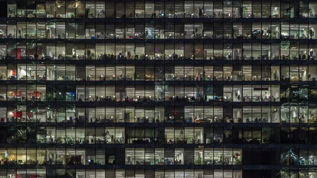 Zooming out view of office windows with working people