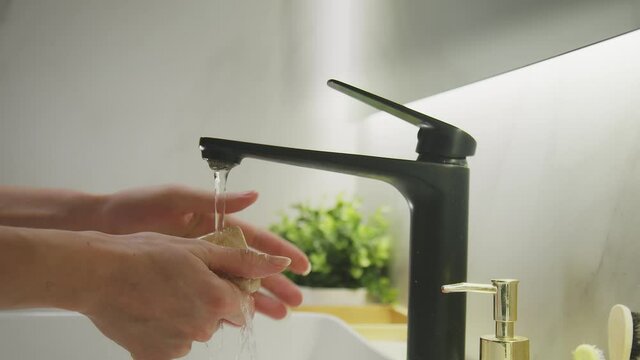 The girl thoroughly washes her hands, soaping them with lumpy soap and rinsing them off with water.