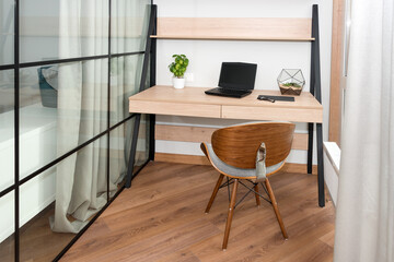 Workplace with laptop on the table. Comfortable work table in office near the window. Design of workplace in home office with modern equipment and objects