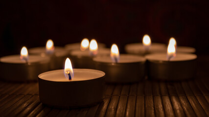 Group of burning candles in the dark with copy space. Romantic concept with tea lights on wooden table