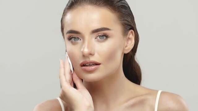 beautiful brunette wiping her face with cotton pad