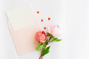 close up top view on blank page postcard invitation paper on pink envelope mail  over white background  and pastel color of heart shape papercut for Mother's Day and valentine season concept