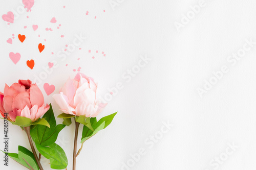 close up top view group of pastel roses on soft pink color background with mini heart and confetti for mother's day and valentine day design concept