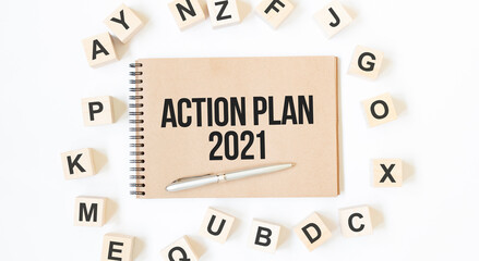 Text ACTION PLAN 2021 on the craft colored notepad with block wood cubes on the white background
