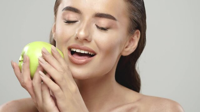 cheerful girl stroking her face with fresh apple