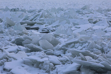Close-up of the ice hummocks on the river near the embankment on a cloudy day as a natural background or texture © Elena