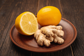 Ginger and lemon in a plate on a wooden background as ingredients for lemonade detox
