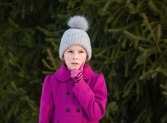 Portrait de fille réfléchie en manteau rose et bonnet tricoté sur fond d& 39 arbres verts