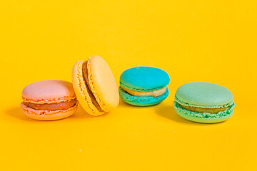 Sweet almond colorful unicorn pink blue yellow green macaron or macaroon dessert cake isolated on trendy yellow modern fashion background. French sweet cookie. Minimal food bakery concept Copy space