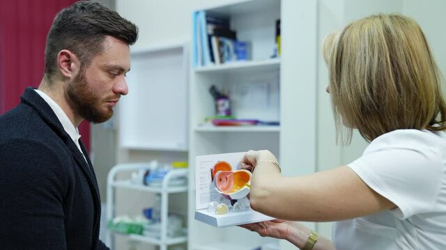 Optical specialist and young man in medical center. Doctor optometrist explaining to a male patient the eye care on an eye layout.