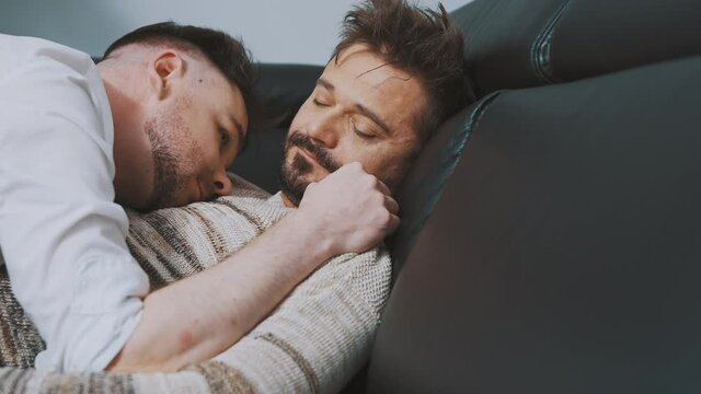 Happy married gay couple snuggling on the couch. Close up. High quality 4k footage