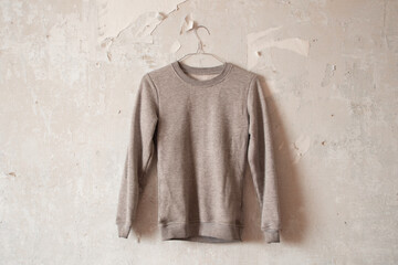 women's gray jacket hanging on a hanger on a white wall close up