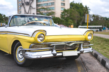 Fototapeta na wymiar front view of a yellow and white vintage car on the streets of havana cuba