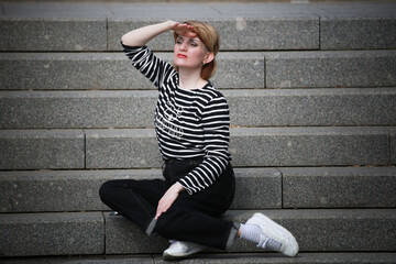 woman in running shoes sitting on stairs and looking away