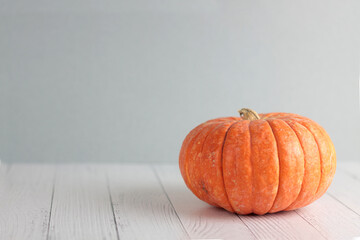 orange puumpkin on white wooden table against gray background