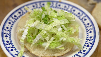 Making a burger at home. Put salad and tomatoes on the bun.