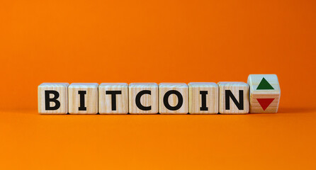 Bitcoin rate symbol. Wooden cubes with the word 'bitcoin' and up and down arrows. Beautiful orange background. Copy space. Business and bitcoin rate concept.