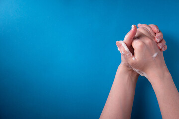 The girl washes her hands with soap, on a blue background, a place for an inscription