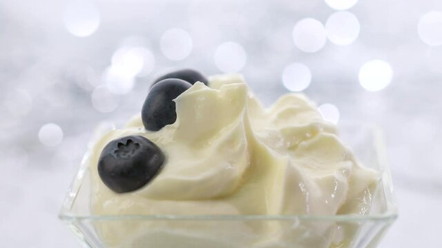 take a spoon of whipped mascarpone cream and blueberries on a silver bokeh festive background