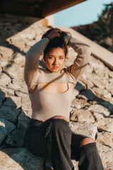 mujer joven adolescente sonriendo sentada en las rocas con color calido de verano.