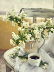 Obraz na płótnie Canvas Jasmine flowers in a white vase. Stillife with jasmine and cup of coffee.