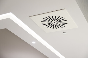 Circular air ventilation grill on the white ceiling