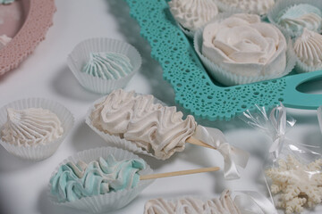 Zephyr on a stick. Marshmallows of different shapes and shades. Close-up shot. On a white table top and a turquoise tray.