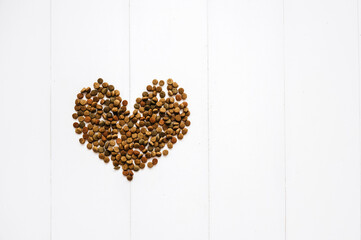 Flat lay Heart shaped cat food on white wooden background