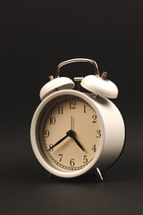 Old-style vintage retro alarm clock on dark black isolated background