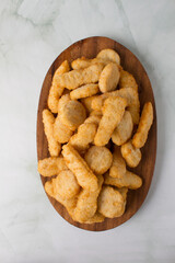 Chickens tenders and nuggets raw, wooden bowl and marmot background