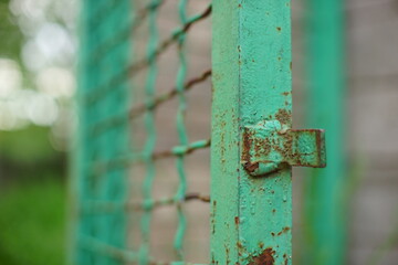 Old open green gate made of welded mesh fence