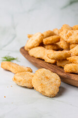 chicken nuggets and chicken tenders, wooden plate with a lot of nuggets. green marmot background