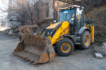 Yellow wheeled tractor excavator. Heavy machinery on a street