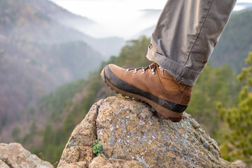 Leg of a man on a rock on a mountain top a view to hills during hiking