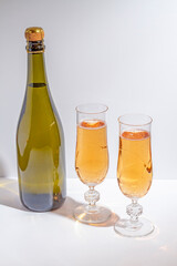 Green bottle with champagne inside and two glasses with champagne 