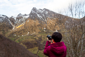 A girl takes pictures of the snowy mountains.