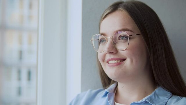 Inspired young woman in eyeglasses smiling, thinking of business idea, student