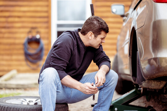 Selective focus shot of a man changing atire of a car