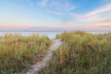 Fototapeta na wymiar sand path trough the dunes towards the ocean under the beautiful sunset sky
