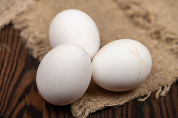 Chicken eggs on a background of homespun fabric with a rough texture. Close-up, selective focus.